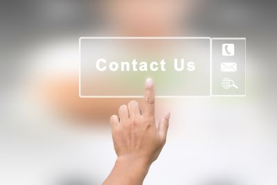 A hand reaching out and touching a translucent \&quot;Contact Us\&quot; button