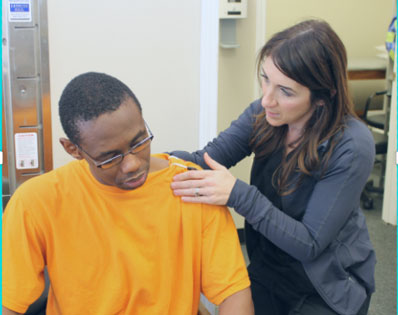 A man standing beside a therapy table holding the lower leg of another man laying on the therapy table