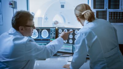 A male doctor pointing out something on a computer screen to another female doctor